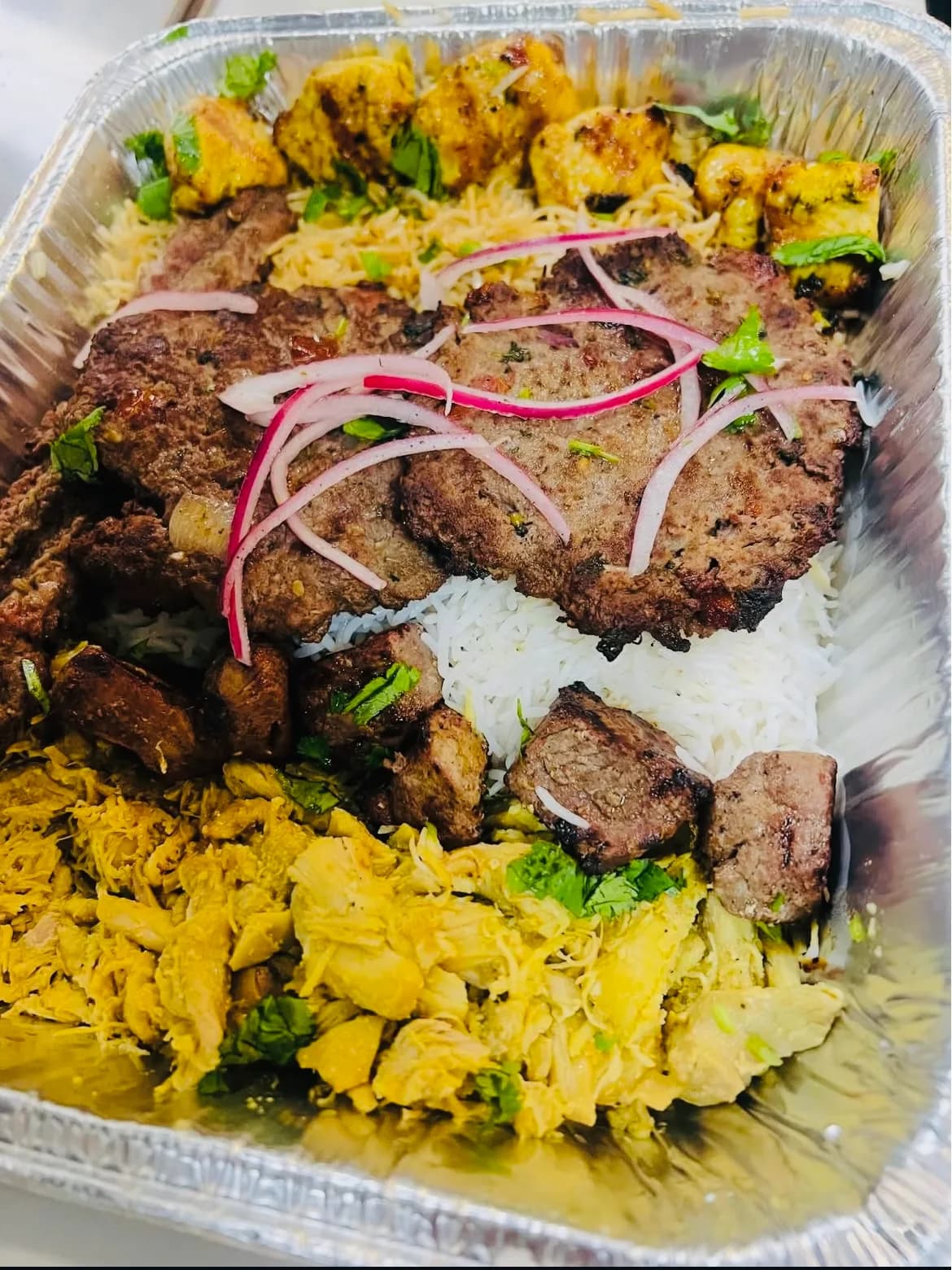 A family platter of mixed kabob over rice with salad and naan